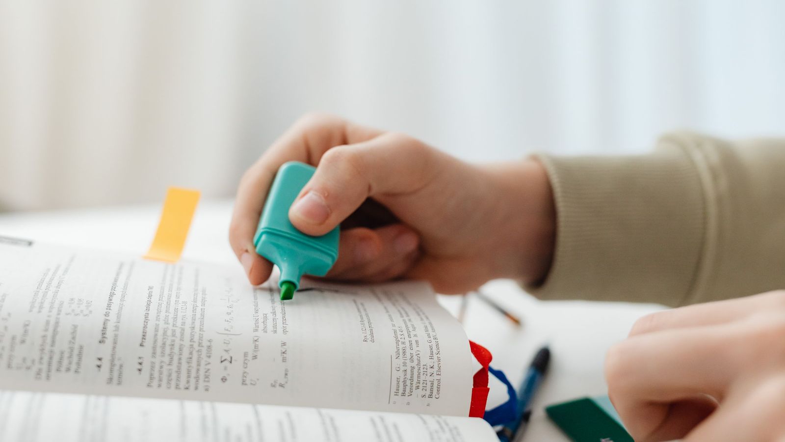 A hand highlighting a line in a textbook with a marker