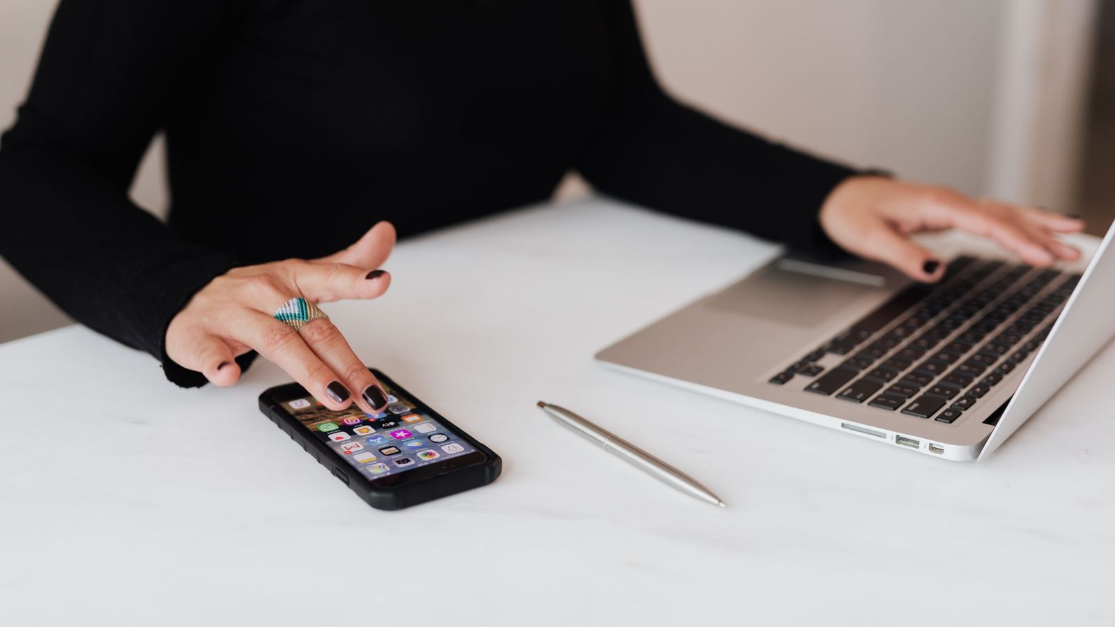 One hand on a phone and the other on a laptop keyboard