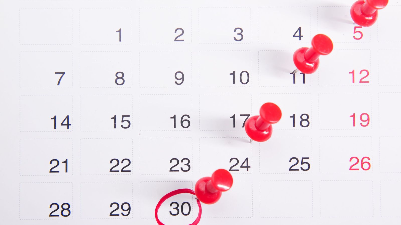 Red pins marking dates spread across a month on a calendar
